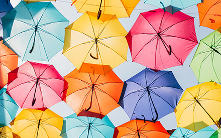 Useita eri värisiä sateenvarjoja alhaalta kuvattuna. 