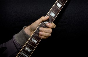 kuvassa käsi kitaran otelaudalla
